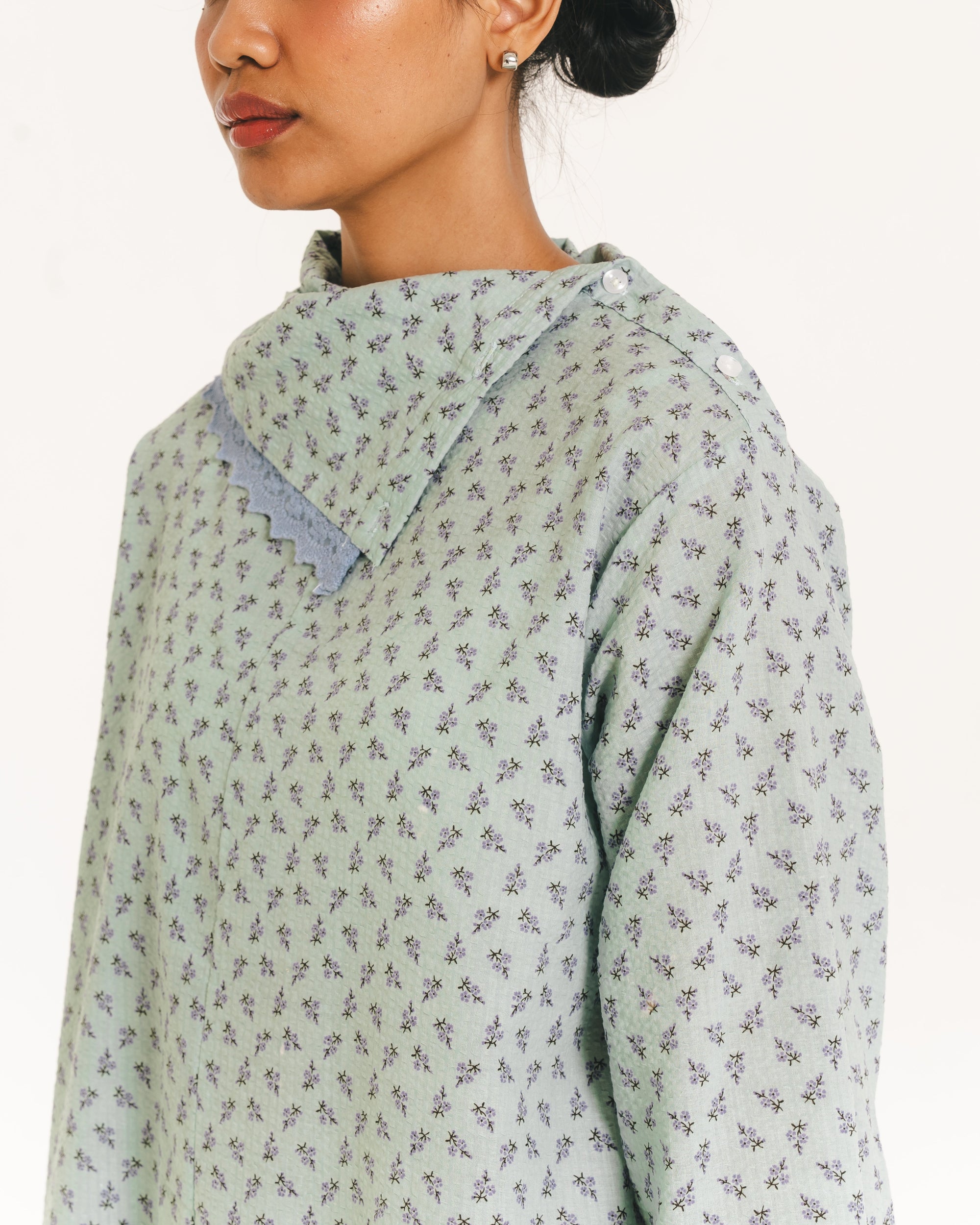 Image of Alice Longsleeve Blouse, a longsleeve blouse with a delicate floral print, featuring an asymmetrical neckline with a folded collar and lace trim accent.