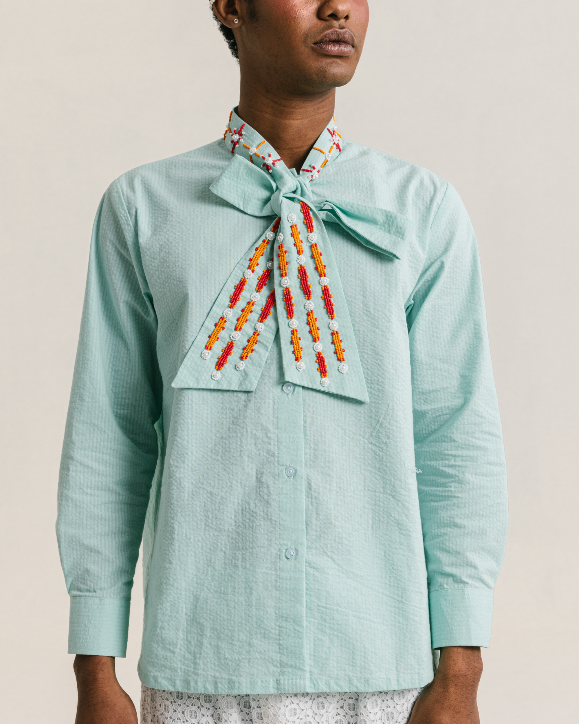 Image of Caspian Bow Shirt Blue, a shirt made from cotton with a hand-beaded collar-tie detail.