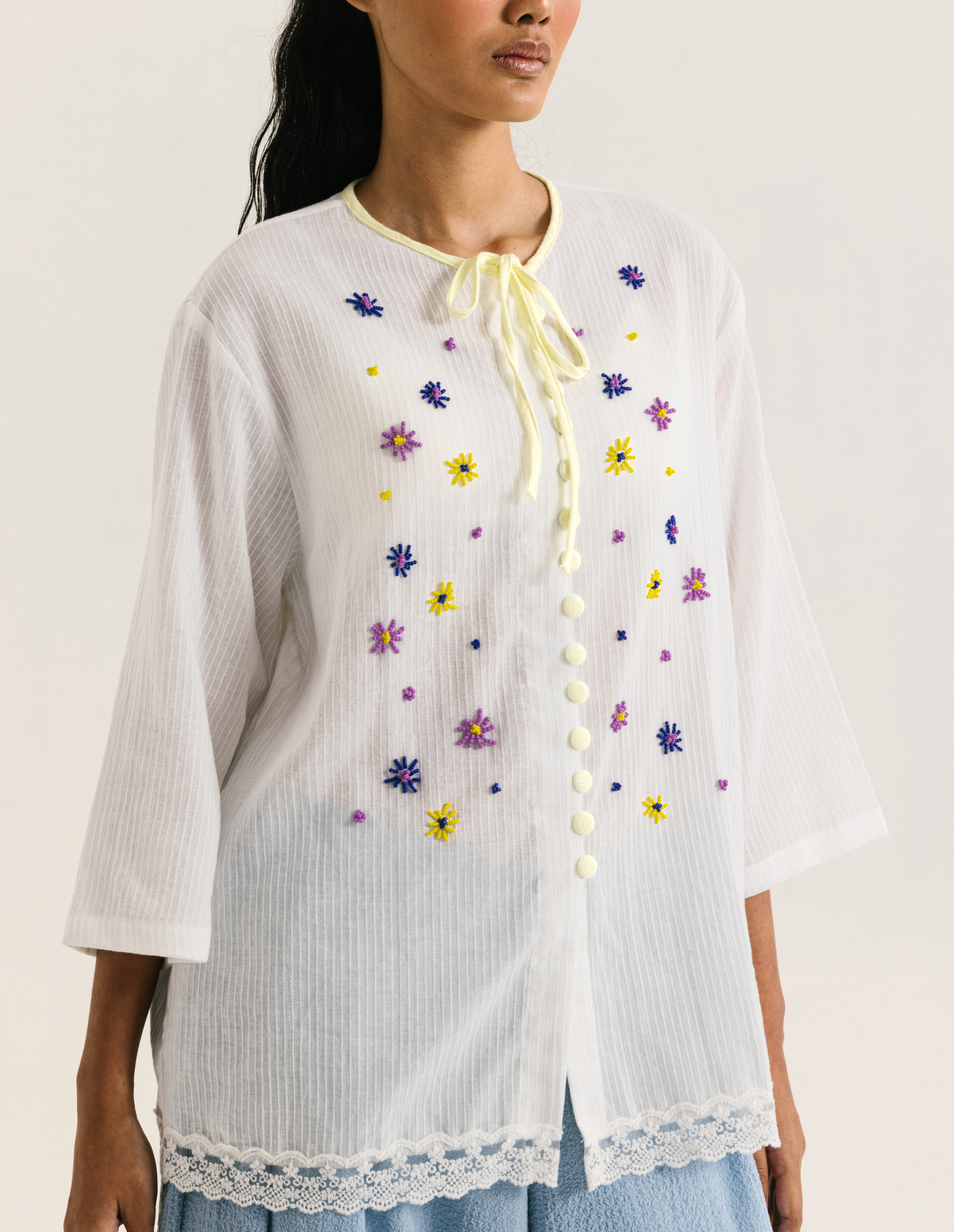 Image of Fleur Longsleeve White, a modest blouse made from cotton-poly, adorned with a hand-beaded flower on the front.