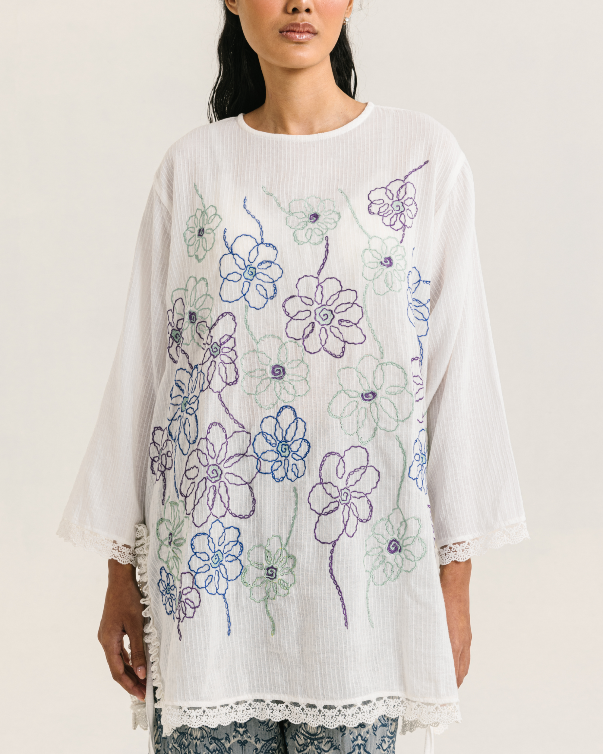 Image of Nora Embroidery Longsleeve White, a loose-fitting tunic made from cotton crepe, embroidered with chic floral design and adorned with delicate lace trims.